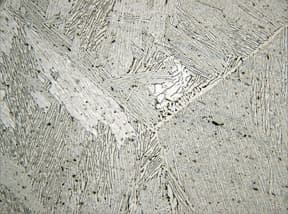 Cast titanium microstructure showing directional solidification patterns similar to AM build direction, demonstrating layer boundaries and grain growth